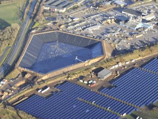 Solarthemriekraftwerk der VOJENS FJERNVARMEVÆRK im dänischen Vojens mit insgesamt 70.000 Quadratmetern Kollektorfläche und 50 MW Leistung. Links ist ein 14 Meter tiefer Wärmespeichr zu sehen, der Warmwasser für den Winter speichert. Foto: Arcon Sunmark