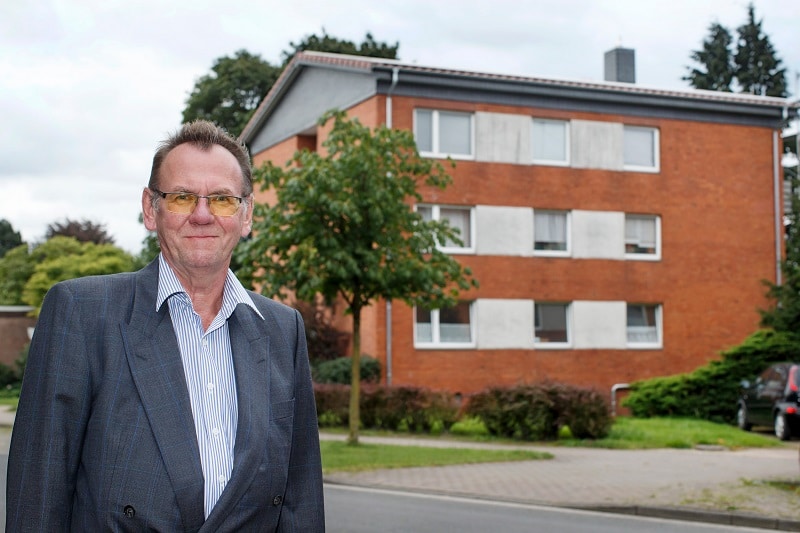 Martin Henne vor dem von ihm energetisch sanierten 6-Familien-Haus. Die Versorgung übernehmen weitestgehend zwei BHKW. Fotos: E3/DC / Andreas Burmann