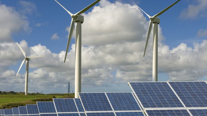 oekostrom Grünes Feld mit Windturbinen und Solaranlagen unter bewölktem und blauem Himmel