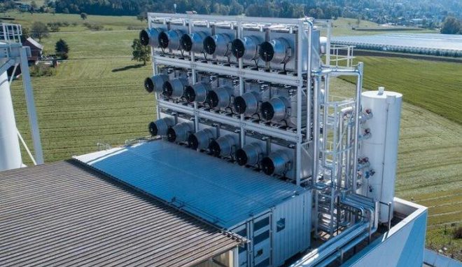 Die DAC-Anlage im Vordergrund und das mit Kohlendioxid gespeiste Gewächshaus im Hintergrund. Climeworks / Julia Dunlop